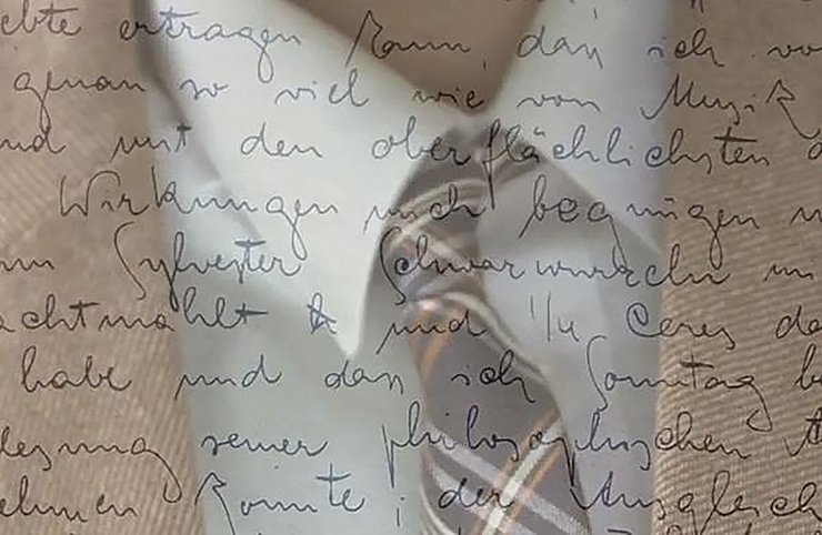Ein Herr mit Anzug und Krawatte ist mit einer Naheinstellung im Bild zu sehen. Der Fokus liegt auf der Krawatte. Darüber liegt ein Bild mit geringer Deckkraft das Schrift oder einen Brief zeigt.