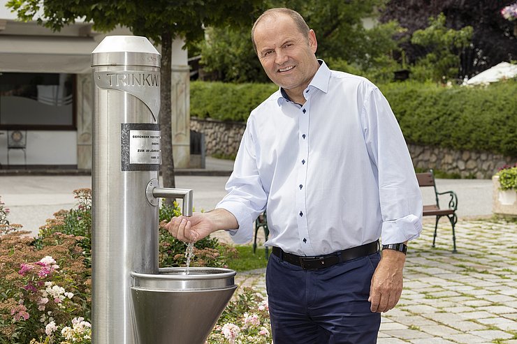 Landeshauptmann-Stellvertreter Geisler füllt Wasser an einem Brunnen ab. 