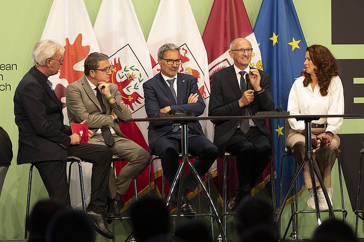 © Land Tirol/Sedlak Personen auf Bühne miteinander redend