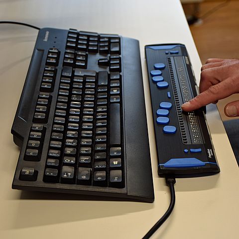 Computertastatur sowie zusätzliche Tastatur zur Anzeige von Bildschirmtexten in Blindenschrift; Finger auf der Tasttatur liegend