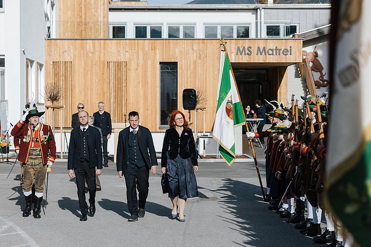 Personen schreiten an Schützenaufstellung vorbei