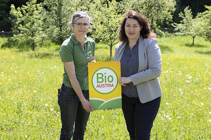 Felipe und Ritter halten Bio Austria-Plakette und stehen in grüner Wiese