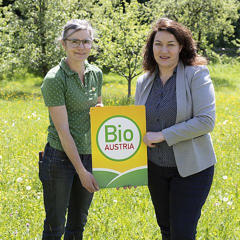 Felipe und Ritter halten Bio Austria-Plakette und stehen in grüner Wiese