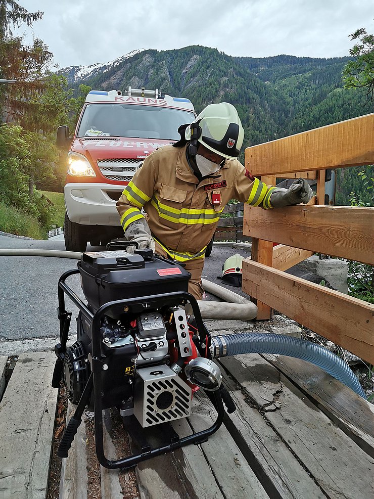 Feuerwehrmann mit Wasserpumpe auf kleiner Brücke