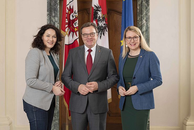 Landeshauptmann-Stellvertreterin Ingrid Felipe, Landeshauptmann Günther Platter und Bundesministerin Margarete Schramböck stehen vor Flaggen des Landes Tirol, Österreichs und der Europäischen Union.