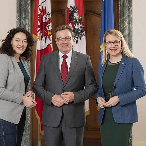 Landeshauptmann-Stellvertreterin Ingrid Felipe, Landeshauptmann Günther Platter und Bundesministerin Margarete Schramböck stehen vor Flaggen des Landes Tirol, Österreichs und der Europäischen Union.