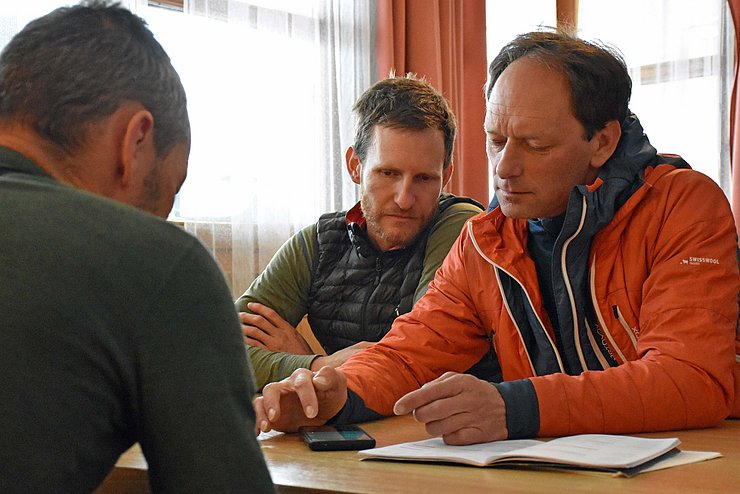 Die Mitarbeiter des Lawinenwarndienstes sitzen am Tisch und planen eine Tour im freien Gelände, um Daten für die Lawinenprognose zu sammeln.