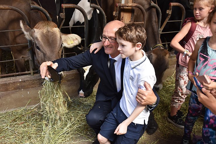 LH Anton Mattle macht ein Selfie mit einem Jungen. Dahinter sind Kühe in einem Stall zu sehen.
