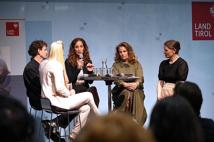 Teilnehmerinnen sitzen im Halbkreis, LRin hat Mikro in der Hand