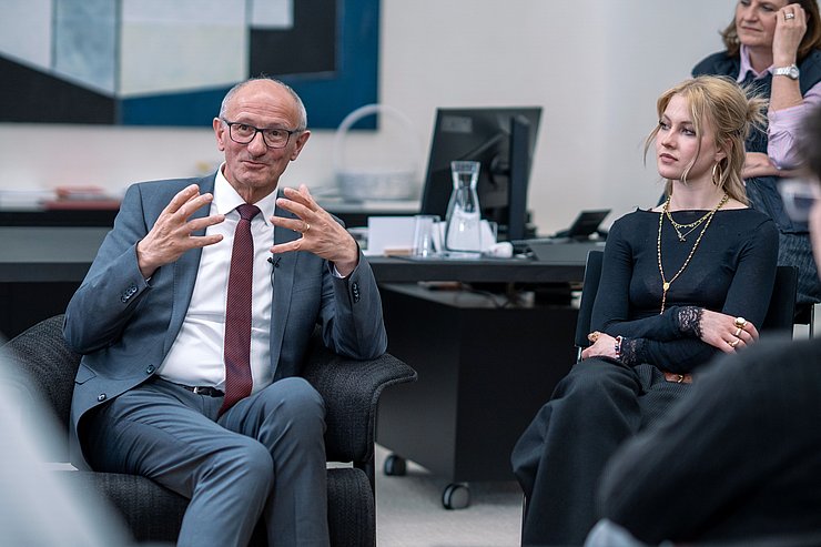 Landeshauptmann sitzt auf Stuhl und gestikuliert mit Händen.