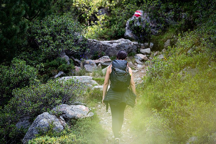 Eine Frau auf einem Wanderweg vor einer rot-weiß-roten Markierung