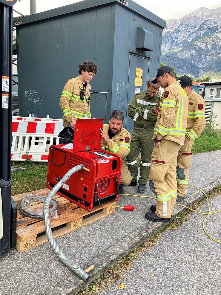 Feuerwehrleute knienen neben Notstromaggregat