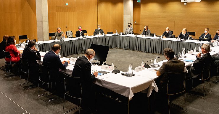 VertreterInnen sitzen an Tischreihen, im Kreis