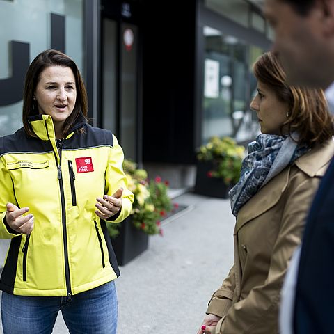 Landesrätin Astrid Mair mit gelber Einsatzjacke im Gespräch mit 2 Personen
