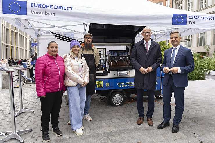 Mehrere Menschen posieren vor einem Stand.