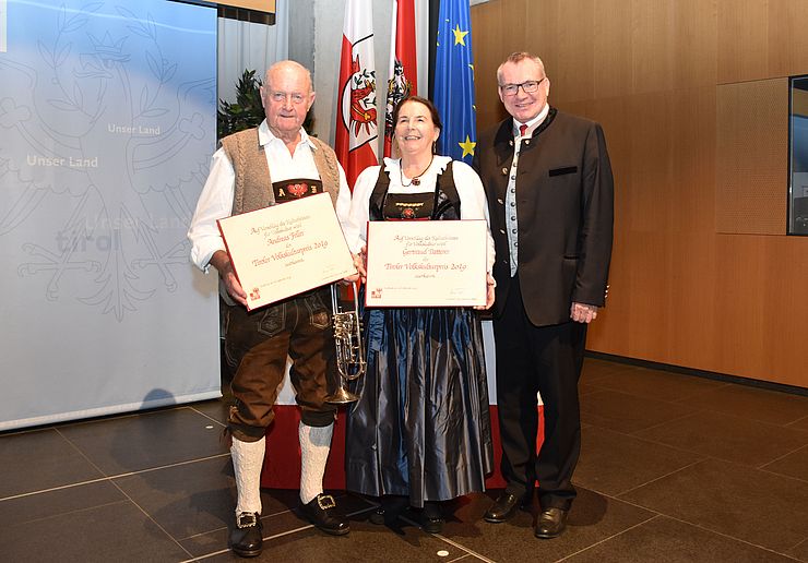 Im Zuge eines offiziellen Festaktes übergibt Landesrat Johannes Tratter (rechts) den Tiroler Volkskulturpreis an Gertraud Patterer sowie Andreas Feller.