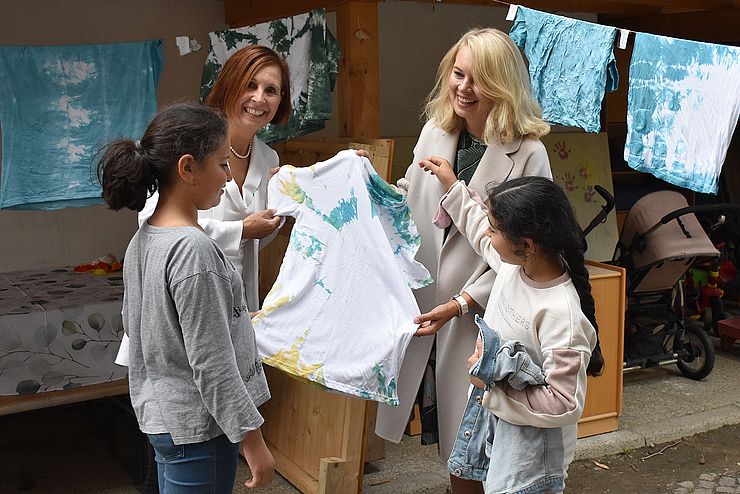 „Die selbst gestalteten T-Shirts sind sehr schön geworden“, gratulieren LRin Gabriele Fischer (li.) und Stadträtin Elisabeth Mayr den Mädchen Widdad und Solav zu ihren gelungenen Erinnerungsstücken an das „SommerLernAbenteuer“.