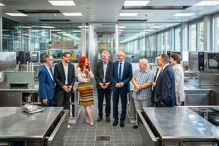 Gruppe steht in Betriebsküche und redet