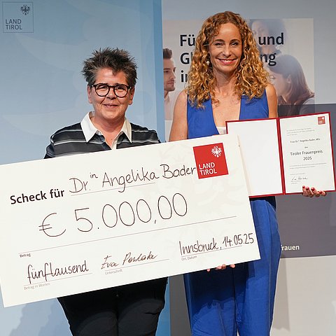 Personen stehen nebeneinander, halten Scheck und Urkunde