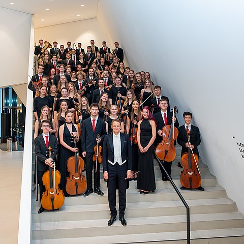 Mehrere junge MusikerInnen stehen auf einer Stiege und halten ihre Instrumente.