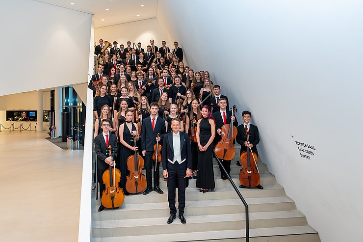 Mehrere junge MusikerInnen stehen auf einer Stiege und halten ihre Instrumente.