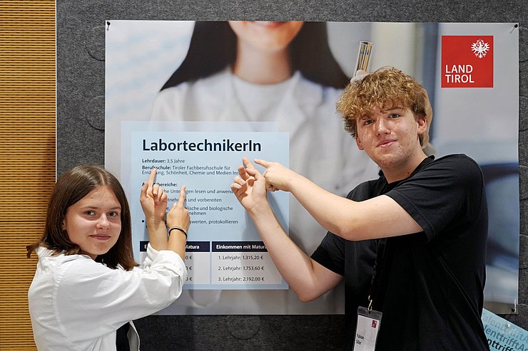 © Land Tirol/Neuner Zwei Lehrlinge zeigen auf Plakat