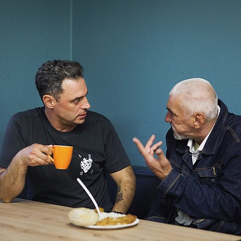 Zwei Personen am Tisch sitzend redend