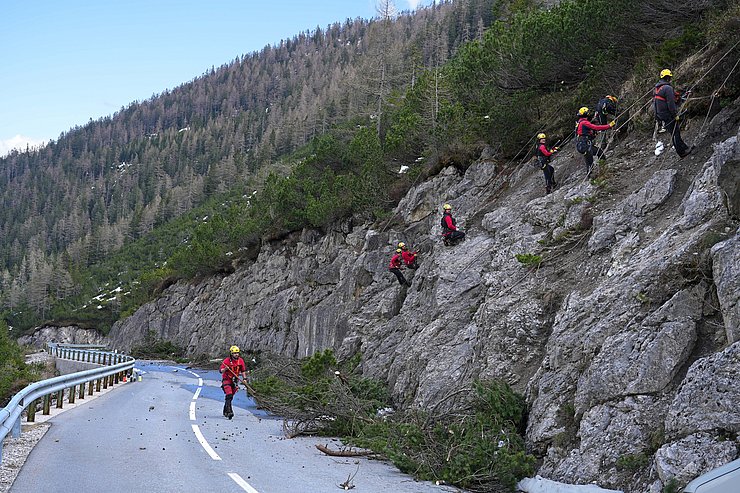 8 Personen hängen mit Seilen an einer Felswand