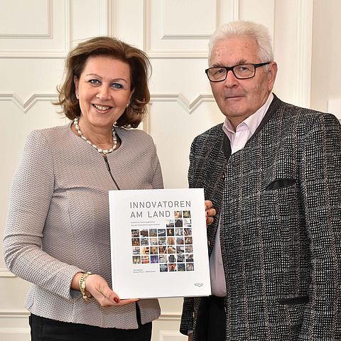 Landesrätin Zoller-Frischauf steht neben Dr. Piock und hält das Buch mit dem Titel "Innovatoren am Land" in der Hand.