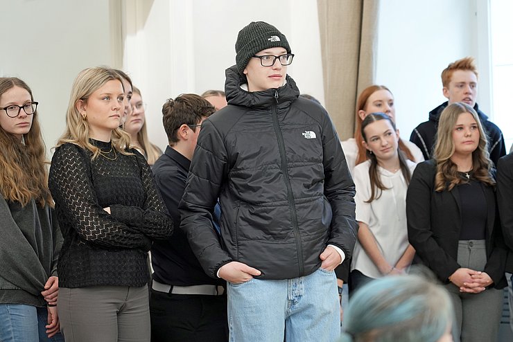 Mehrere junge Menschen stehen und blicken in dieselbe Richtung. 