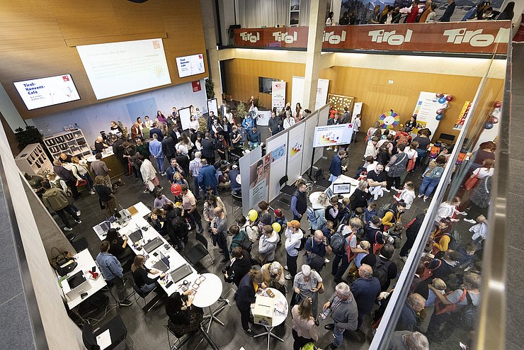 Blick in den großen Saal von oben, dort stehen viele Menschen.