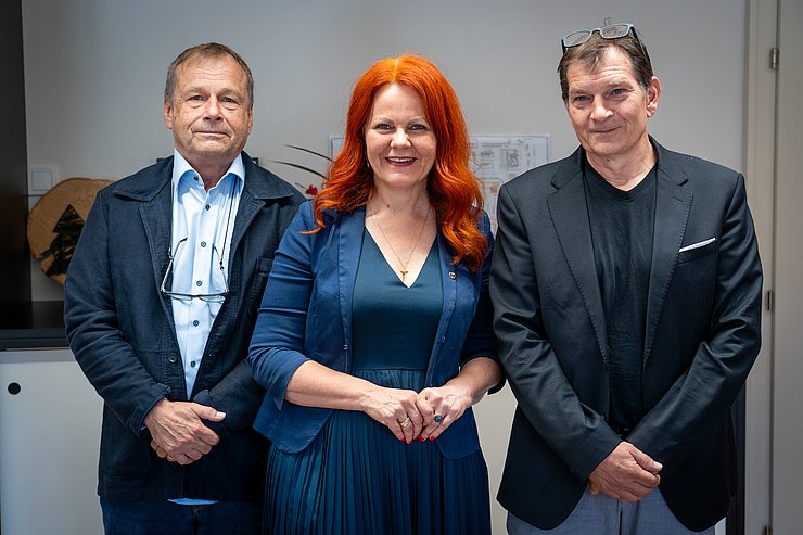 © Land Tirol/Neuner Eine Frau mit roten Haaren steht in der Mitte, flankiert von zwei Herren.
