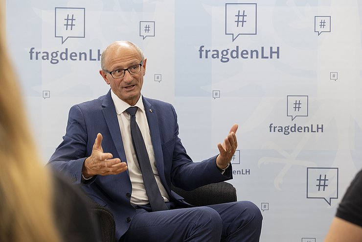 LH Anton Mattle sitzt auf einem Stuhl und beantwortet die Fragen der Schülerinnen.
