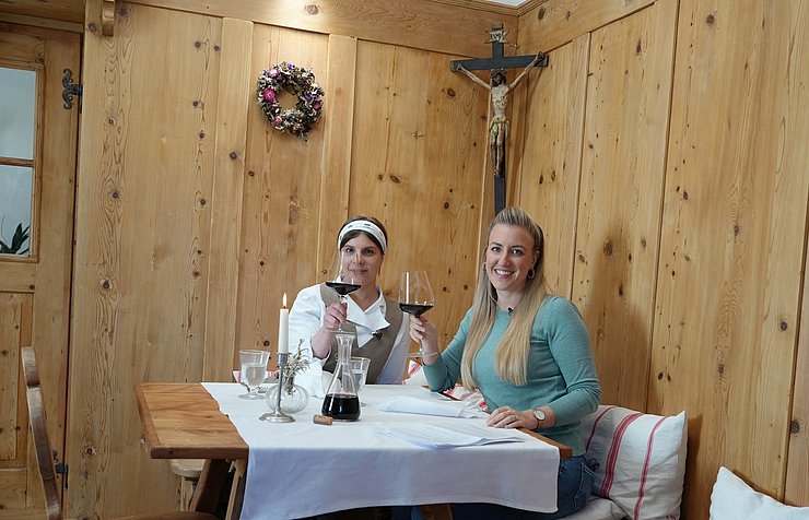Sitzen auf Ecktisch in hölzerner Stube, heben Weinglas