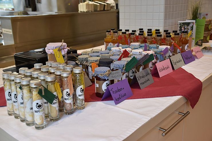 Produkte, wie Kräutersalz, Marmeladen und Chutneys auf einem Tisch präsentiert