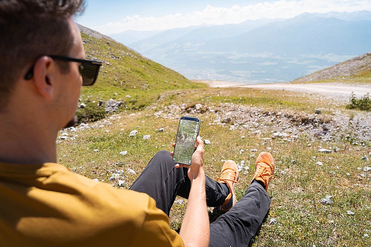 Person mit Handy in der Hand auf der eine Wanderkarte zu sehen ist