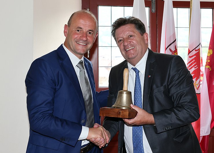 Schöpf und Gianmoena halten die Glocke des Euregio-Rates der Gemeinden
