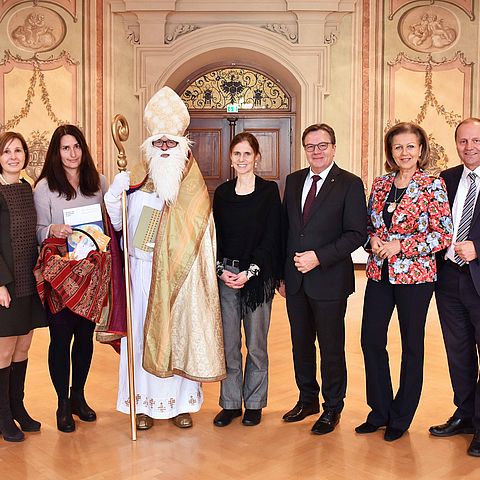 Die Regierungsmitglieder stehen zusammen mit dem Nikolaus im Parissaal im Landhaus.