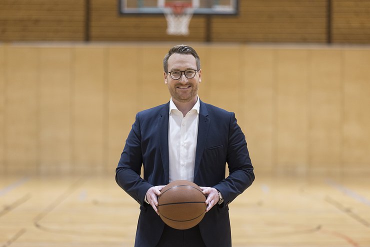 Portrait Wohlgemuth mit Basketball in Sporthalle