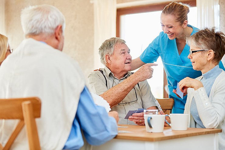 © Land Tirol/Shutterstock Pflegerin hat Spaß mit einer Gruppe Senioren