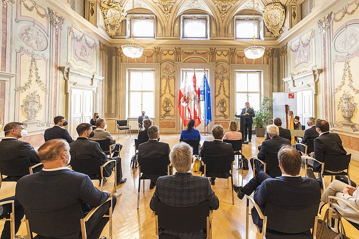 Parissaal: Menschen auf Stühlen sitzen, Ernst Schöpf vor Rednerpult