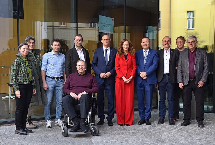 Gruppenfoto - Personen nebeneinander im Freien vor Glaswand