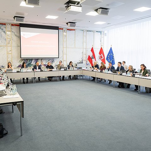 Raum mit großem Tisch an dem Menschen setzen