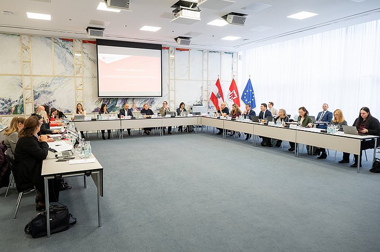 Raum mit großem Tisch an dem Menschen setzen