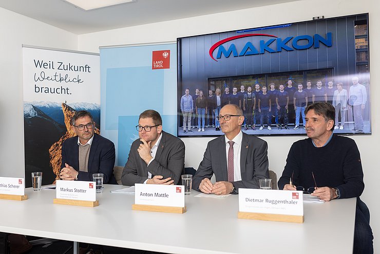 4 Männer sitzend vor Tisch mit Namensschilder