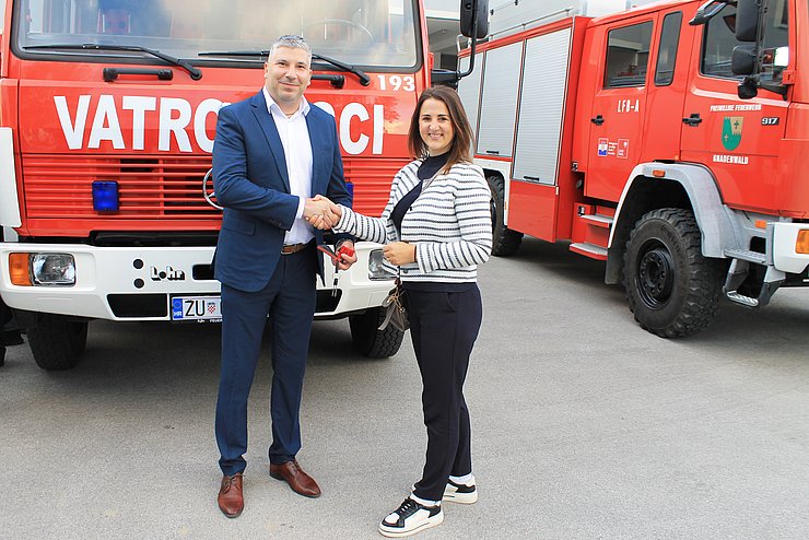 Mair und Mann vor Auto stehend Hand schüttelnd 