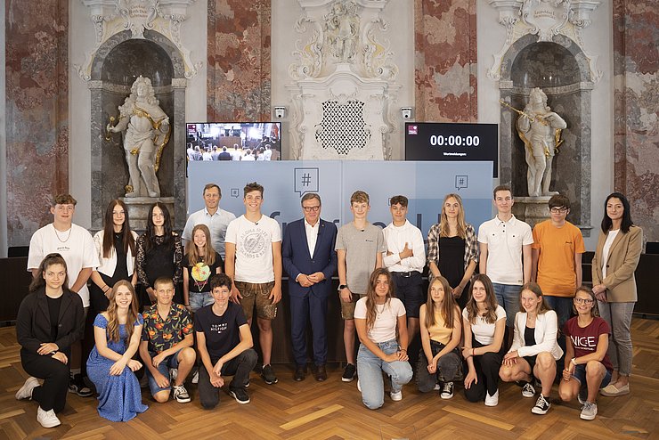 Die SchülerInnen der Polytechnischen Schule Brixen im Thale und LH Günther Platter stellen sich für das Gruppenfoto im Landtagssitzungssaal auf.