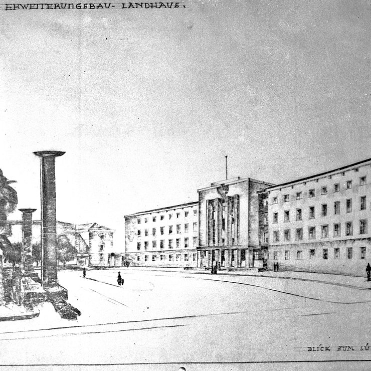 Eine Zeichnung des Siegesprojektes von Walther und Ewald Guth: Eine symmetrische Südfassade, aus der ein Mittelrisalit für den Eingangsbereich hervorragt. Dem gegenüber zwei mächtige Pylonen, die das Platzende markrieren. So der Blick von der Wilhelm-Greil-Straße.