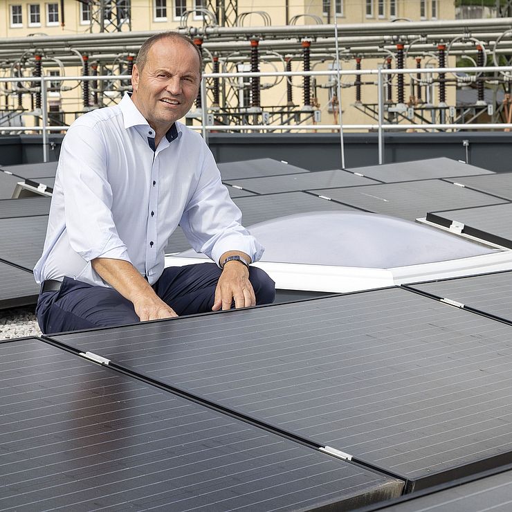 Energielandesrat Geisler befindet sich zwischen Photovoltaik-Elementen auf einem Dach.