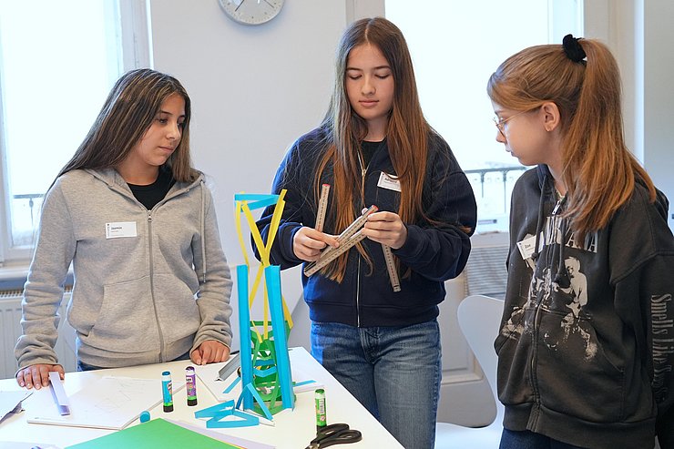 Mädchen mit Messband, vor Turm aus Papier